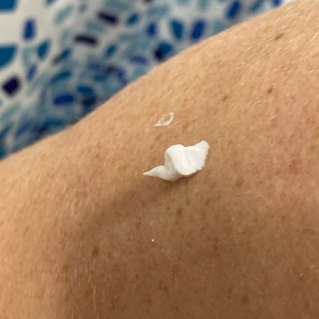 Gota de base blanca recién puesta sobre el brazo de una clienta