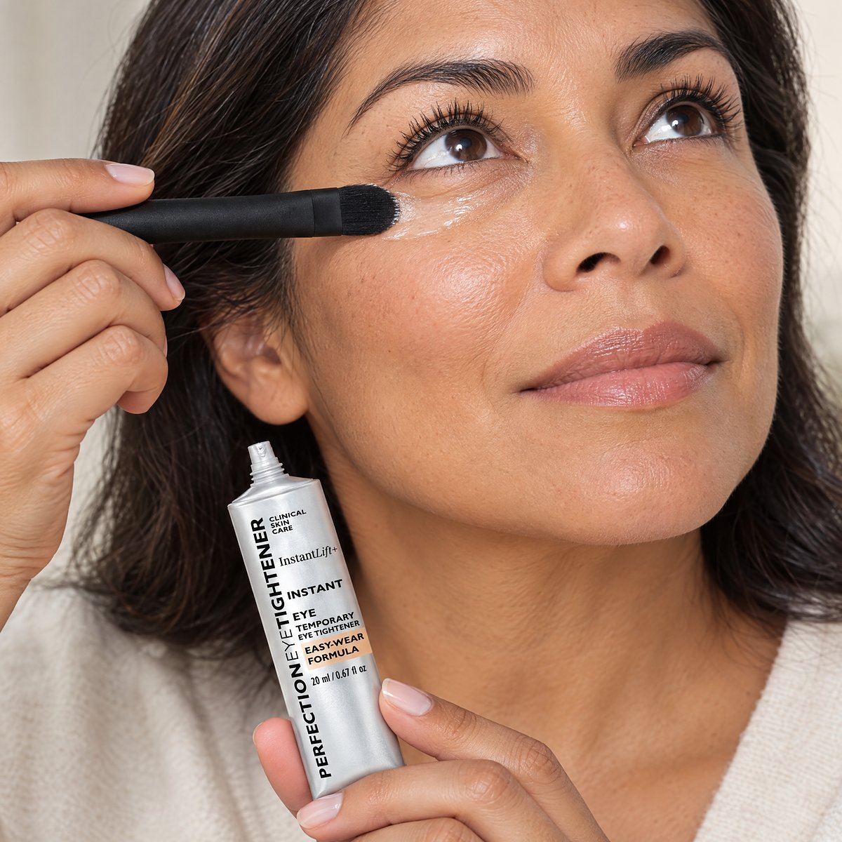 Mujer aplicando el tensor EyeLift con pincel bajo el ojo
