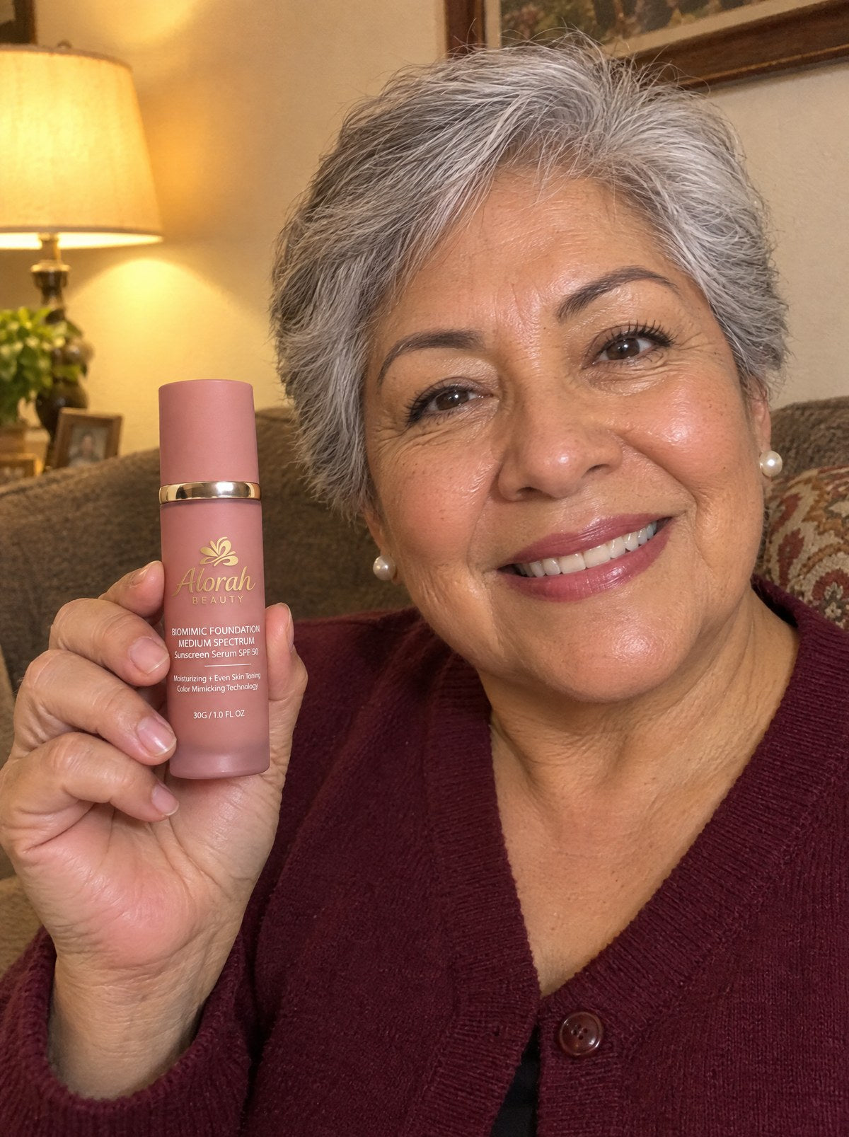 Mujer sonriendo en su sala con la base 4 en 1 de Alorah Beauty en la mano